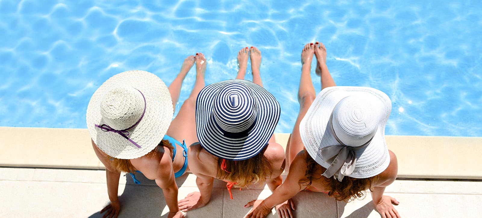 three women lounging in front of pool